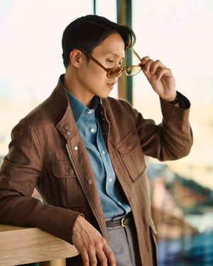 Brown Field Jacket with Light Grey Trousers and Blue Shirt